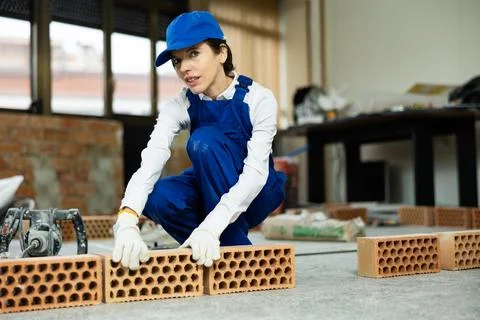 Female builder arranging bricks inside building under construction Stock Photos