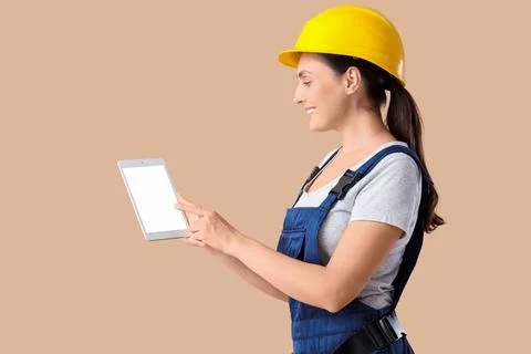 Female builder with blank tablet computer on beige background Stock Photos