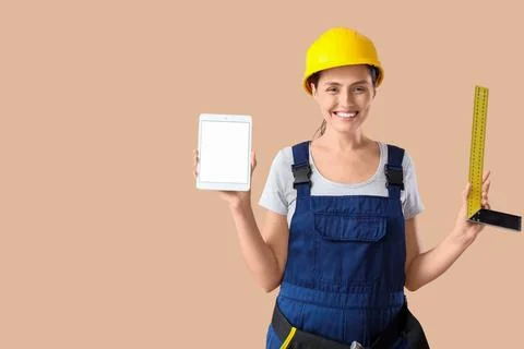 Female builder with blank tablet computer and ruler on beige background Stock Photos