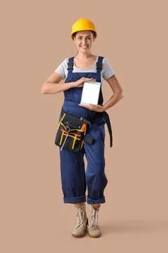 Female builder with blank tablet computer on beige background Stock Photos