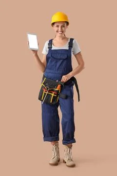 Female builder with blank tablet computer on beige background Stock Photos