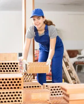 Female builder stacking bricks at construction site 写真素材