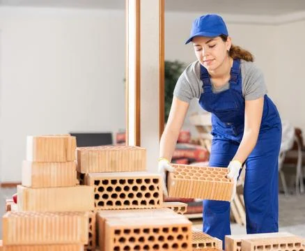 Female builder stacking bricks at construction site Stock Photos