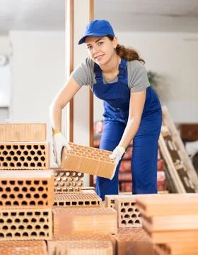 Female builder stacking bricks at construction site Stockfoto's