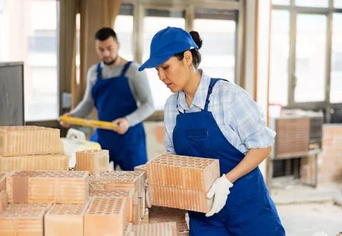 Female builder stacking red bricks at construction site indoors Stock Photos