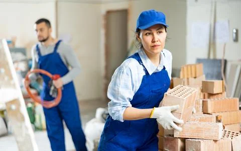 Female builder stacking red bricks at construction site indoors Stock Photos