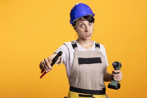 Female builder stands in fighting pose with drill and wrench Stock Photos