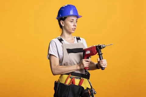 Female builder using drill gun and showing repairing ability Stock Photos