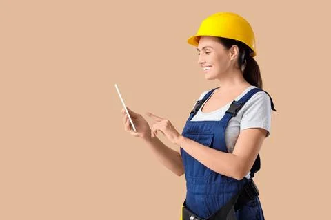 Female builder using tablet computer on beige background Stock Photos