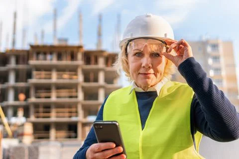 A female builder worker at a construction site works and controls the process. Stock Photos