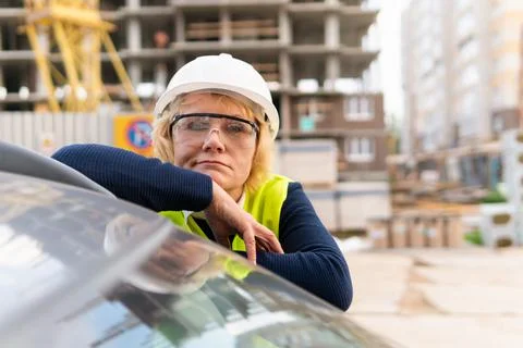 A female builder worker at a construction site works and controls the process. Stock Photos