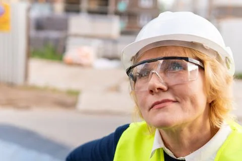 A female builder worker at a construction site works and controls the process. Stock Photos