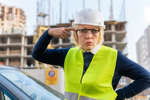 A female builder worker at a construction site works and controls the process. Stock Photos