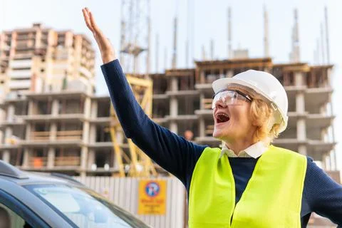 A female builder worker at a construction site works and controls the process. Stock Photos