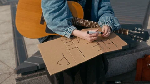 Female Busker Writing Help Me Message and Placing It Nearby Stock Footage 315280632