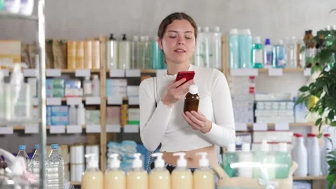 Female buyer scans code on cough syrup to check the expiration date Stock Footage 332636421