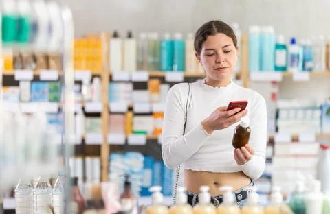 Female buyer scans code on cough syrup to check expiration date Photos