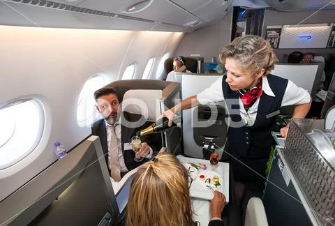 Female cabin crew pouring a glass of champaign in business class of an Airbus Stock Photos