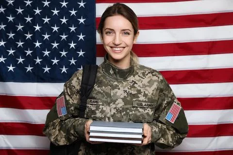 Female cadet with backpack and books against American flag. Military educatio Stock Photos