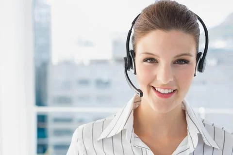 Female call center agent in button-up shirt talking on headset at office window, Stock Photos