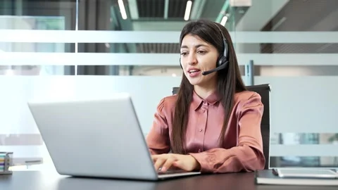 Female call center operator wearing headset working in office, talking to client 動画素材 332849448