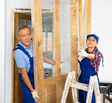 Female carpenter pointing with the hand while a repairman in uniform dragging Foto stock