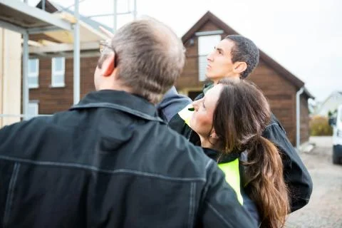 Female Carpenter Pointing While Standing By Colleagues At Site 写真素材