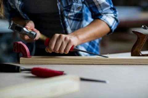 Female carpenter using chisel on wooden plank Foto stock