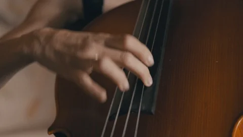 A female cellist plucks the strings of a cello while playing in a string Video stock 92504556