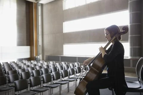 Female cellist practicing on stage in empty auditorium Stock Photos