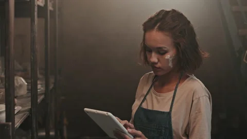 Female Ceramist Using Tablet by Rack Stock Footage 169862233