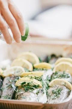 Female chef adding salt to fish dish. Photos