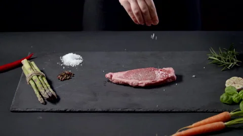 Female Chef Applying Grained Salt And Rosemary Herbs On Raw Piece Of Steak Stock Footage 170241224