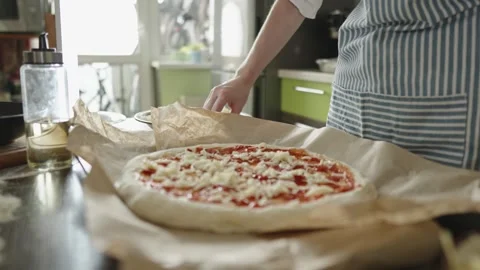 Female chef in an apron is putting mozzarella cheese on a raw pizza Stock Footage 280158882