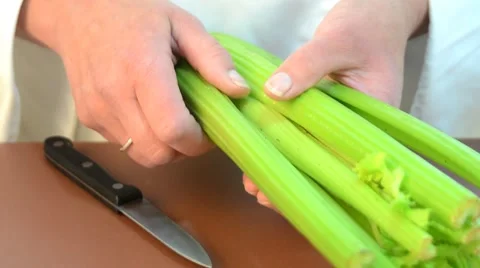 Female chef cleaning celery with a kitchen knife Stock Footage 8829570