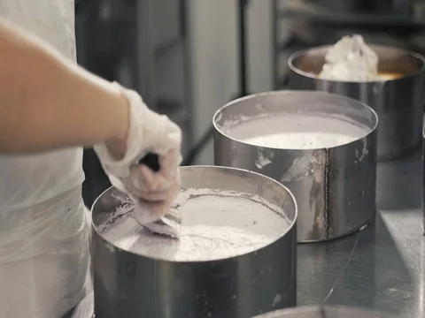 Female chef cook in rubber gloves preparing vanilla cake-mix dough in form for Stock Footage