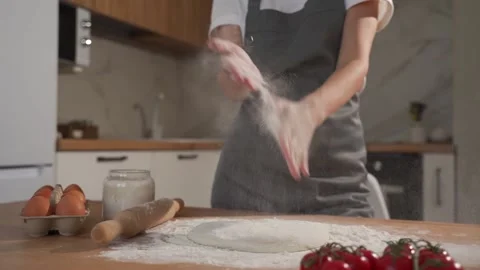 Female chef in a gray apron claps her hands with splashes of white flour on the Video stock 211626815