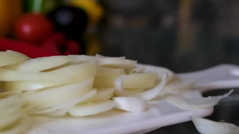 Female chef is precisely slicing fresh onions on wooden board while preparing Stock Footage 302109869