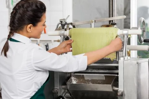Female Chef Processing Ravioli Pasta In Machinery At Kitchen Stock Photos
