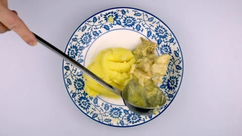 A female chef's hand puts mashed potatoes into a plate with a spoon. Stock-Footage 262238032