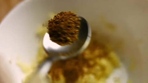 Female chef's hands adding hmeli-suneli to pressed garlic cloves in a bowl Stock Footage 151428645