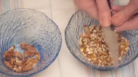 Female chef's hands chopping nuts to the glass plate closeup Stock Footage 74462404