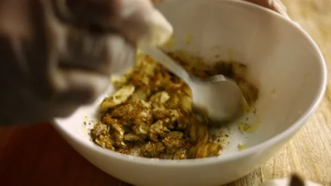 Female chef's hands mixing pressed garlic cloves with spices in a bowl Stock Footage 151428738
