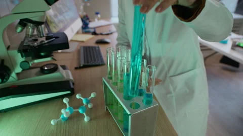 Female Chemist Analyzing Sample under Microscope and Taking Empty Test Tube Stock Footage 332359016