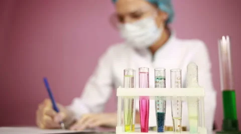 Female chemist comparing test tubes with chemicals. protective glasses Stock Footage 64659493