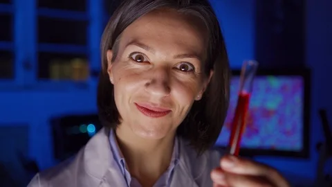 Female chemist examining liquid in test tube and smiling at camera Stock Footage 124715352