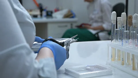 A female chemist in a laboratory opens a package with scissors containing a Vídeo Stock 121688936