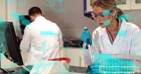 Female chemist using pipette aspirating fluid for prep while male typing data Stock Footage 310318856