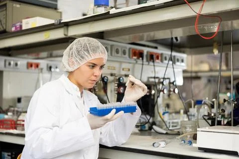 Female chemist working in laboratory, analyzing liquid samples in test flasks Stock Photos