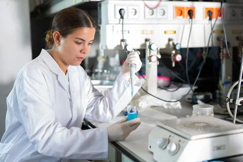 Female chemist working in laboratory, analyzing liquid samples in test flasks Stock Photos